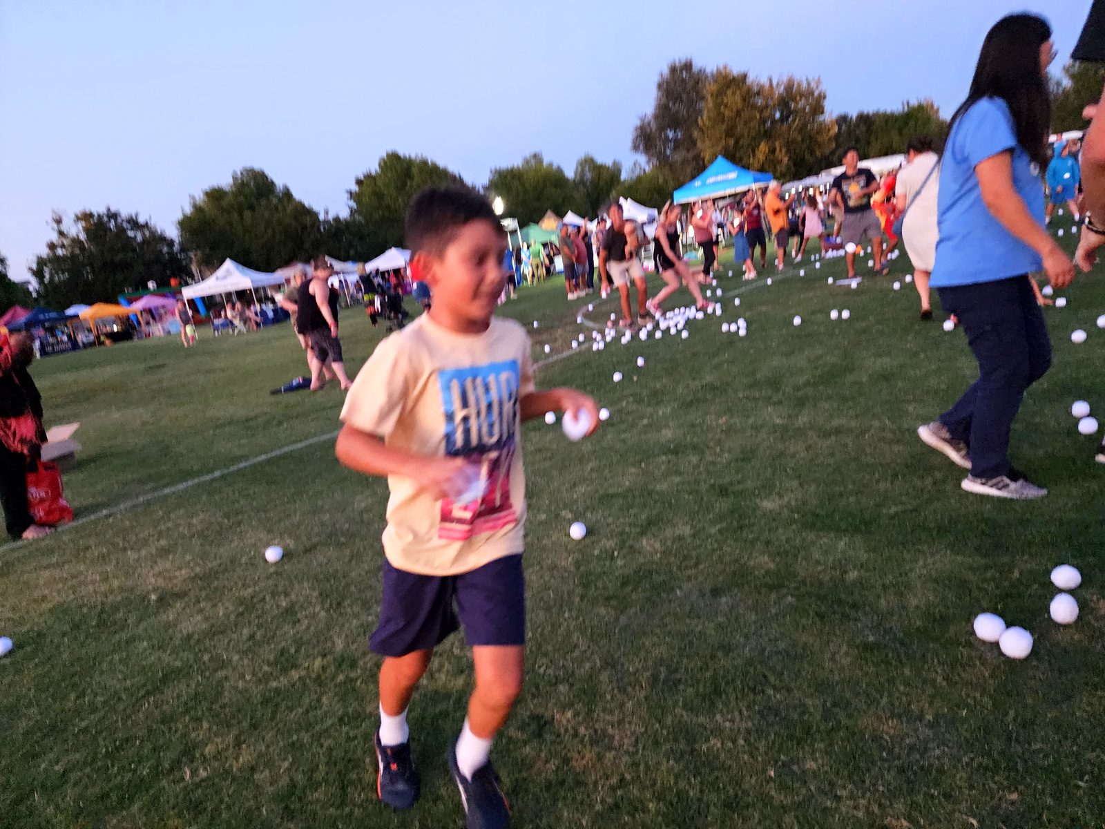 A child running across the grass chasing a ball at the Family Fun Fest, off the screen and into the game